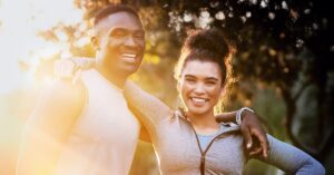 smiling male and female runners with sunlight behind them