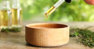 Golden coloured oil in pipette dropper over bowl with green background